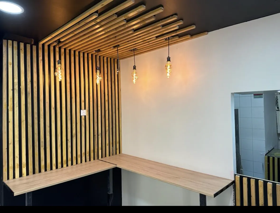 Habillage mural en tasseaux de bois avec suspensions lumineuses